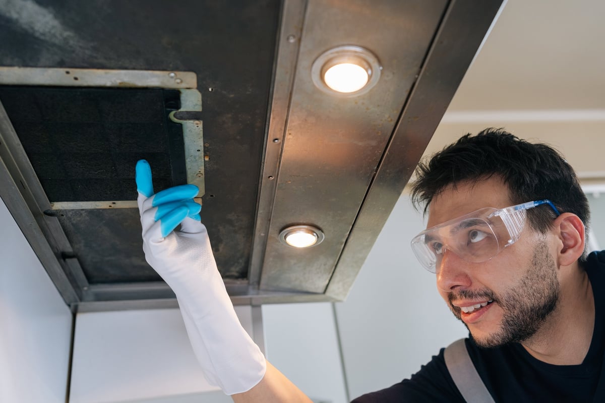 Professional HVAC technician performing duct cleaning and maintenance inspection