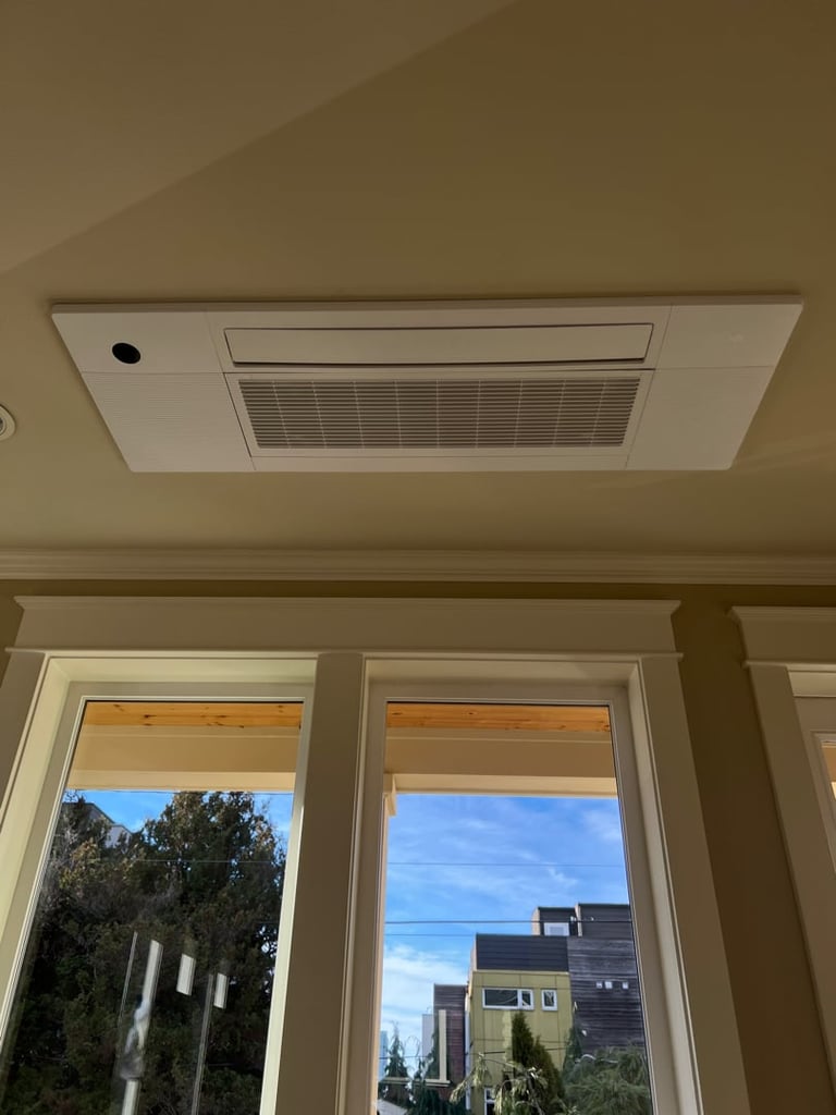Ceiling-mounted bathroom exhaust fan above two windows showing outdoor view with trees and residential buildings
