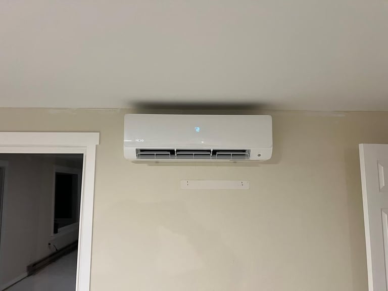 White split-type air conditioning unit mounted on beige wall between two white-framed doorways in an indoor room
